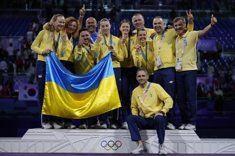Ukraine's fencers Olga Kharlan, Alina Komashchuk, Olena Kravatska and Yuliia Bakastova celebrate on the podium with their team after winning the gold medal in the women's team sabre competition during the 2024 Summer Olympics at the Grand Palais, Saturday, Aug. 3, 2024, in Paris, France. (AP Photo/Andrew Medichini)