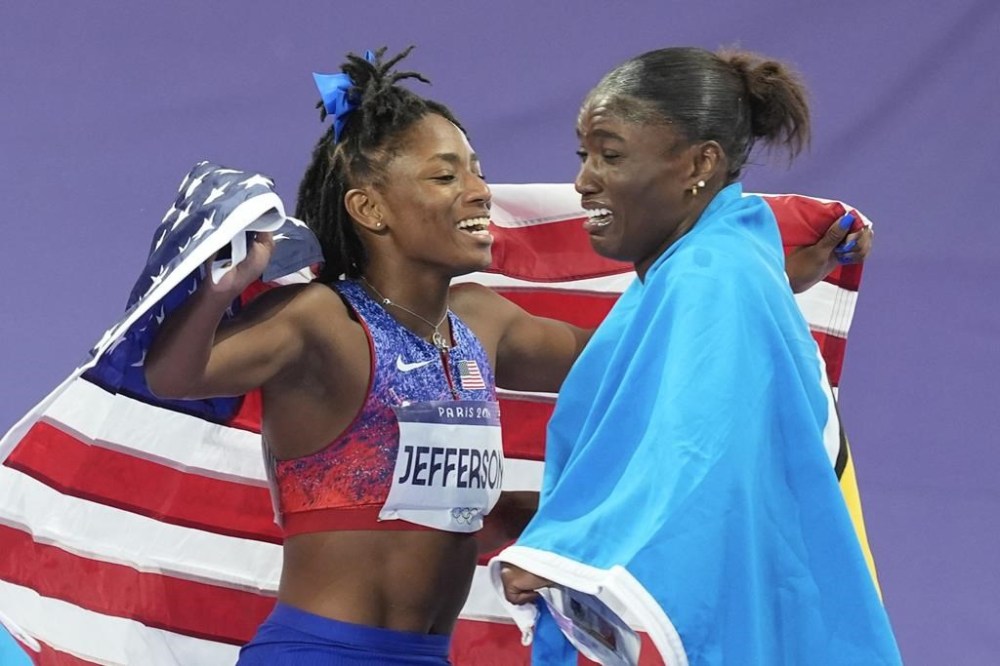 Gold medal winner Julien Alfred, of Saint Lucia, right, celebrates along with bronze medalist Melissa Jefferson, of the United States, after winning the women's 100-meter final at the 2024 Summer Olympics, Saturday, Aug. 3, 2024, in Saint-Denis, France. (AP Photo/Rebecca Blackwell)