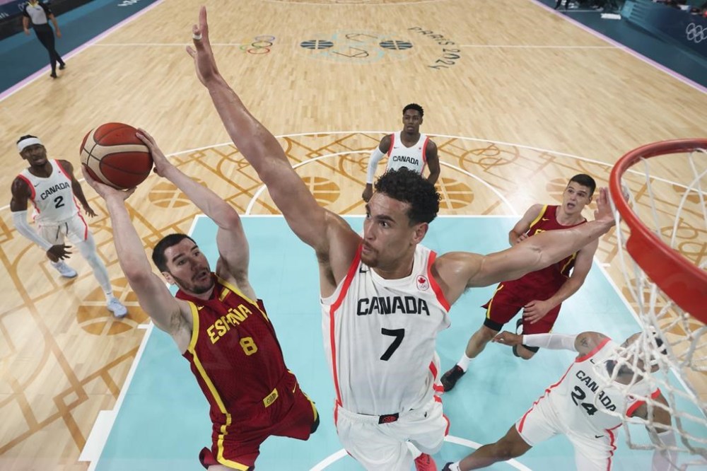 Darío Brizuela, of Spain, shoots over Dwight Powell, of Canada, in a men's basketball game at the 2024 Summer Olympics, Friday, Aug. 2, 2024, in Villeneuve-d'Ascq, France. (Gregory Shamus/Pool Photo via AP)
