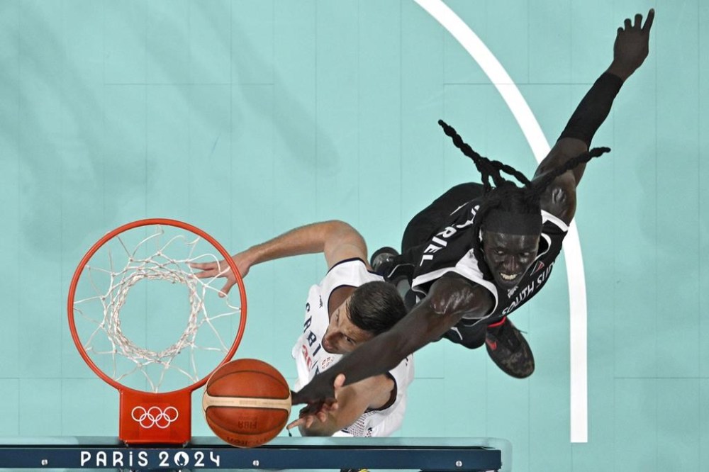Serbia's Aleksa Avramovic, left, shoots as South Sudan's Wenyen Gabriel defends at the 2024 Summer Olympics, Saturday, Aug. 3, 2024, in Villeneuve-d'Ascq, France. (Sameer Al-Doumy/Pool Photo via AP)