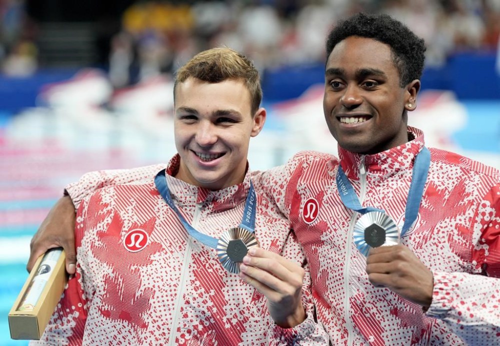 Canada's Josh Liendo, right, of Toronto, poses with the silver medal he won alongside fellow Canadian Ilya Kharun, of Montreal, who won bronze, both in the 100m men's butterfly final during the 2024 Summer Olympic Games, in Nanterre, France, Saturday, Aug. 3, 2024. THE CANADIAN PRESS/Christinne Muschi