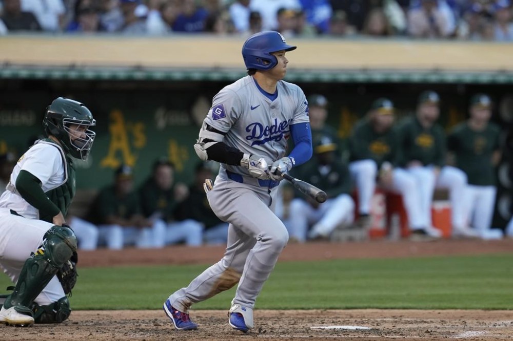 Los Angeles Dodgers' Shohei Ohtani, right, starts to run after hitting a single against the Oakland Athletics during the fifth inning of a baseball game Saturday, Aug. 3, 2024, in Oakland, Calif. (AP Photo/Godofredo A. Vásquez)
