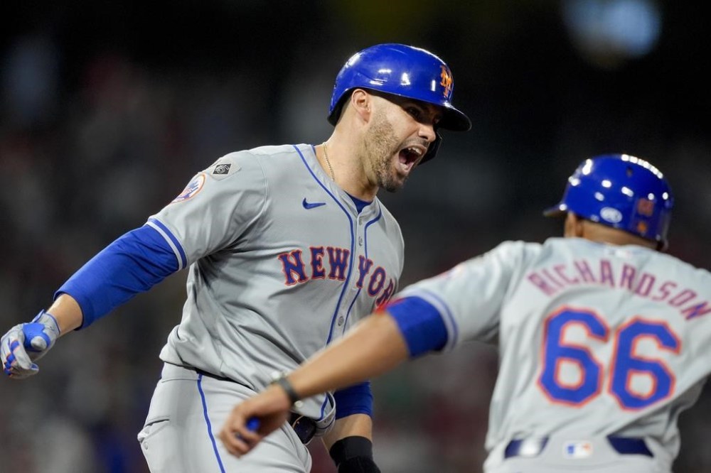 New York Mets designated hitter J.D. Martinez, left, reacts with first base coach Antoan Richardson (66) after hitting a grand slam during the seventh inning of a baseball game against the Los Angeles Angels, Saturday, Aug. 3, 2024, in Anaheim, Calif. (AP Photo/Ryan Sun)