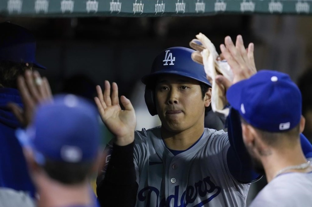 Los Angeles Dodgers' Shohei Ohtani, center, celebrates with teammates in the dugout after scoring against the Oakland Athletics on Amed Rosario's single during the ninth inning of a baseball game Saturday, Aug. 3, 2024, in Oakland, Calif. (AP Photo/Godofredo A. Vásquez)