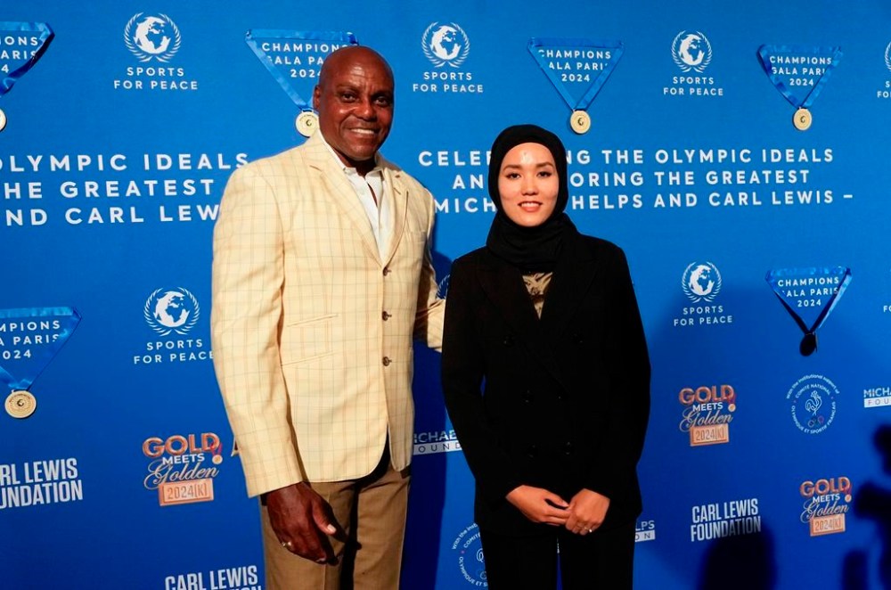 Former Olympian Carl Lewis, left, and representer of the IOC's Refugee Olympic Team Masomah Ali Zada arrives for the Sport for Peace Gala in Paris, Saturday, Aug. 3, 2024. (AP Photo/Michel Euler)