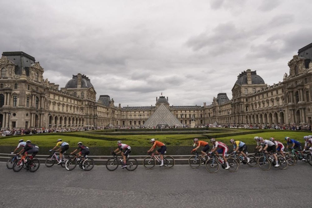 Cyclists ride past the Louvre museum as they compete in the men's road cycling event, at the 2024 Summer Olympics, Saturday, Aug. 3, 2024, in Paris, France. (AP Photo/Thibault Camus)