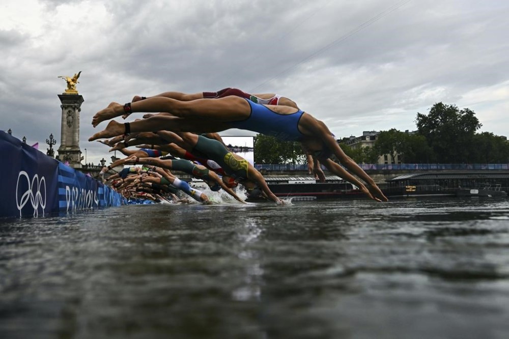 Athletes compete in the swimming race in the Seine during the women's individual triathlon at the 2024 Summer Olympics, Wednesday, July 31, 2024 in Paris, France. (Martin Bureau/Pool Photo via AP)