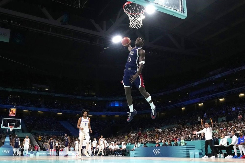 United States' Anthony Edwards, center, goes up for a dunk as Puerto Rico's Stevie Thompson Jr. watches during a men's basketball game at the 2024 Summer Olympics, Saturday, Aug. 3, 2024, in Villeneuve-d'Ascq, France. (AP Photo/Michael Conroy)