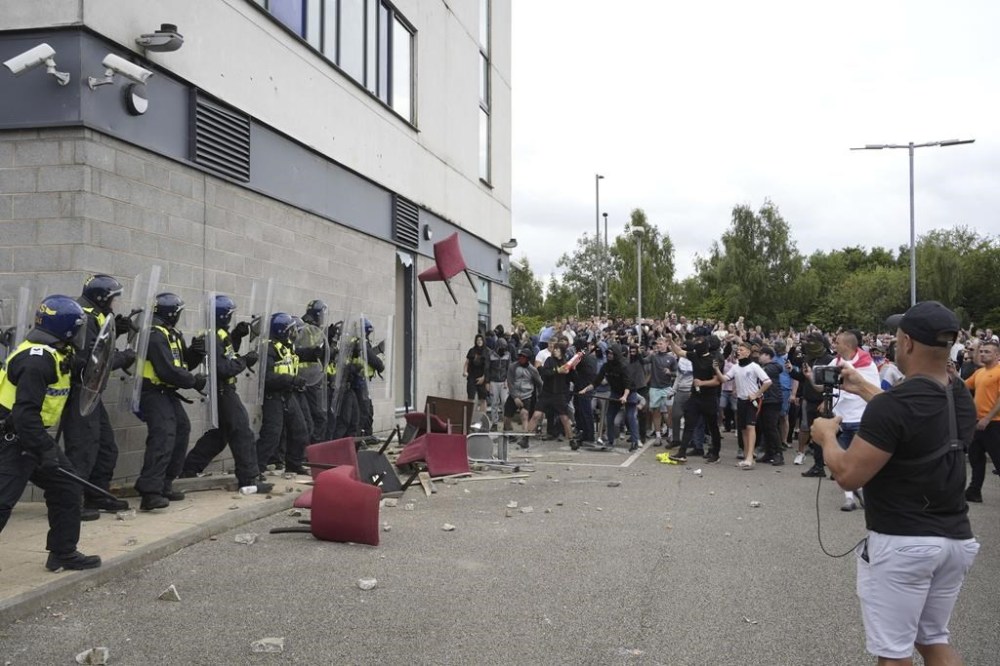 A chair is thrown at police officers as trouble flares during an anti-immigration protest outside the Holiday Inn Express in Rotherham, England, Sunday Aug. 4, 2024. (Danny Lawson/PA via AP)