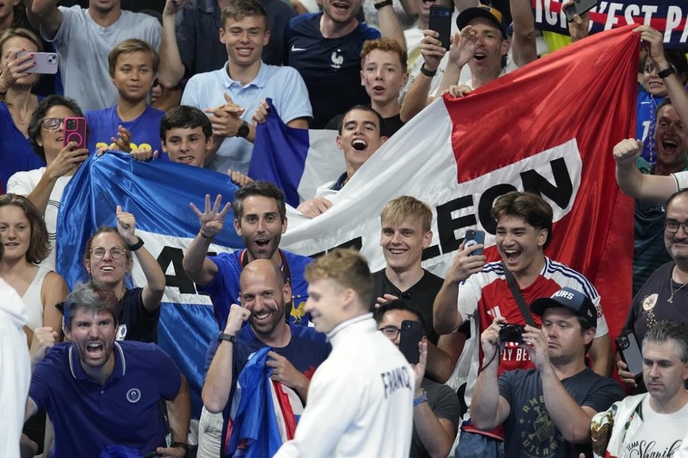 Supporters of Leon Marchand of France, react as he receives his gold medal for the men's 200-meter individual medley final at the 2024 Summer Olympics, Friday, Aug. 2, 2024, in Nanterre, France. (AP Photo/Ashley Landis)