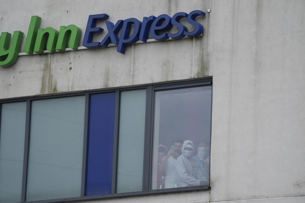 People watch from a window inside the Holiday Inn Express as an anti-immigration demonstration takes place outside the hotel, in Rotherham, England, Sunday Aug. 4, 2024. (Danny Lawson/PA via AP)