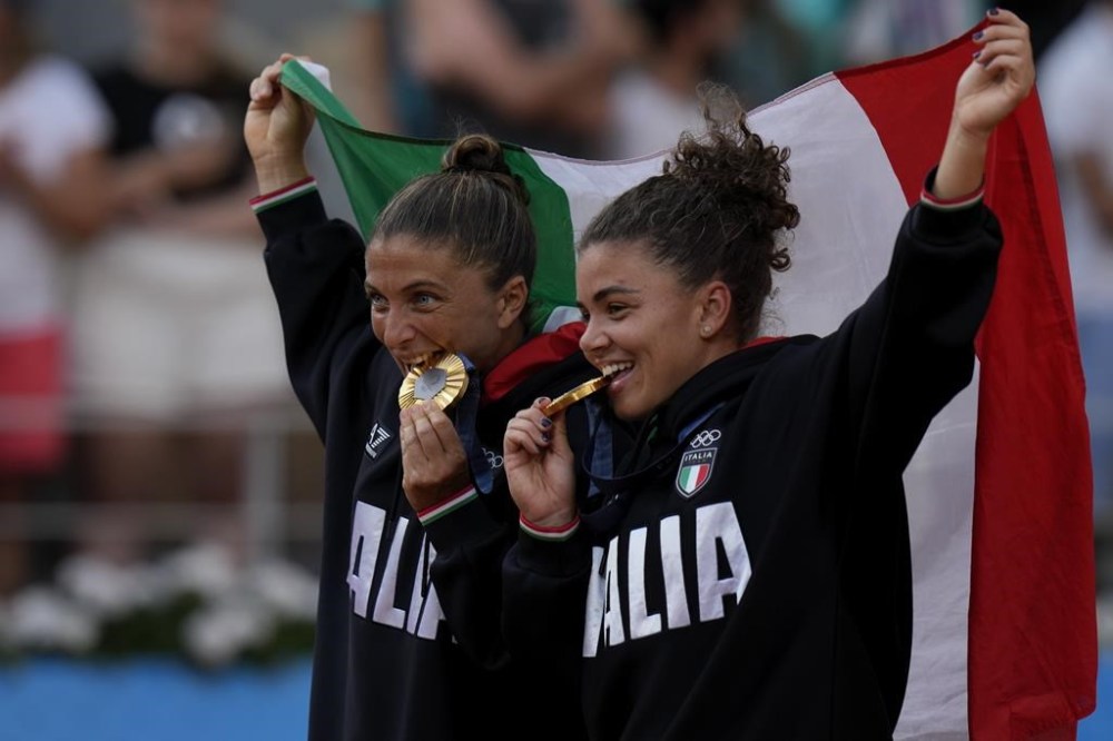 Gold medalist Sara Errani and Jasmine Paolini of Italy bite their medal after they defeat Mirra Andreeva and Diana Shnaider of Individual Neutral Athlete in the women's doubles gold medal tennis match at the Roland Garros stadium, at the 2024 Summer Olympics, Sunday, Aug. 4, 2024, in Paris, France. (AP Photo/Andy Wong)