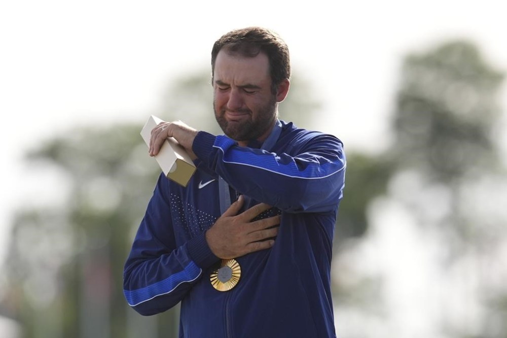 Gold medalist Scottie Scheffler, of the United States, cries as the national anthem of the US is played during the medal ceremony for men's golf at the 2024 Summer Olympics, Sunday, Aug. 4, 2024, at Le Golf National in Saint-Quentin-en-Yvelines, France. Scottie Scheffler, of the United States, won the gold medal with Tommy Fleetwood, of Britain, silver and Hideki Matsuyama, of Japan, the bronze.(AP Photo/George Walker IV)