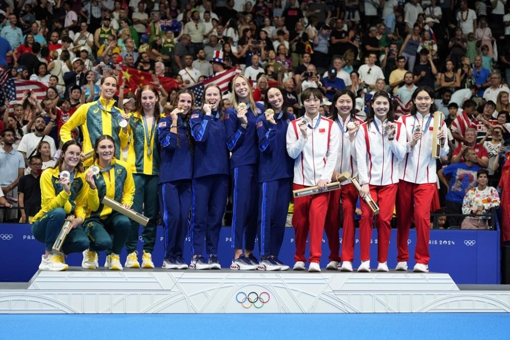 United States' gold medalists pose for a photo on the podium with Australia's silver medalists and China's bronze medalists during the awards ceremony for the women's 4x100-meter medley relay at the Summer Olympics in Nanterre, France, Sunday, Aug. 4, 2024. (AP Photo/Natacha Pisarenko)