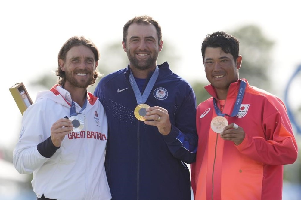 Gold medalist Scottie Scheffler, of the United States, centre, with Tommy Fleetwood, of Britain, silver medal, and Hideki Matsuyama, of Japan, with the bronze medal pose for the media following the medal ceremony for men's golf at the 2024 Summer Olympics, Sunday, Aug. 4, 2024, at Le Golf National in Saint-Quentin-en-Yvelines, France. (AP Photo/George Walker IV)
