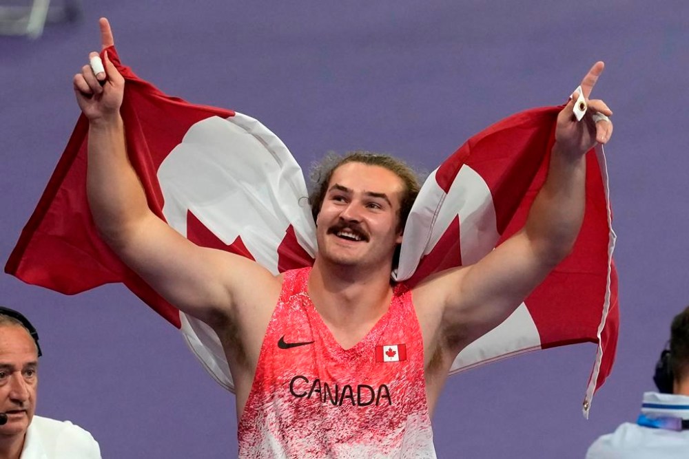 Ethan Katzberg, of Nanaimo, B.C., celebrates after winning gold in the men's hammer throw event at the 2024 Summer Olympics, Sunday, Aug. 4, 2024, in Saint-Denis, France. THE CANADIAN PRESS/Adrian Wyld