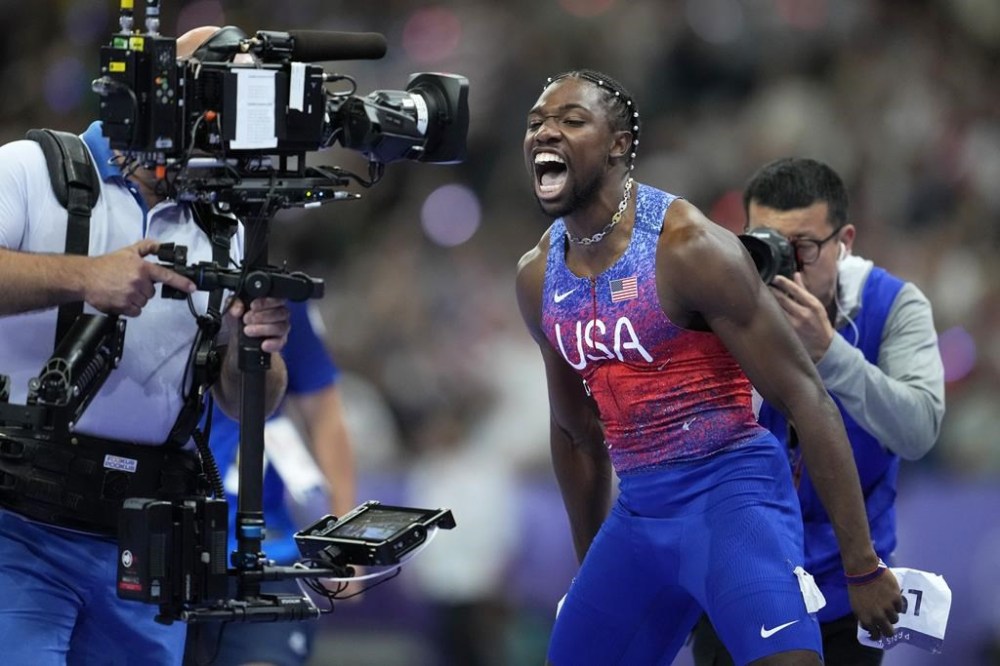Noah Lyles, of the United States, screams at a tv camera celebrating after winning the gold medal in in the men's 100 meters final at the 2024 Summer Olympics, Sunday, Aug. 4, 2024, in Saint-Denis, France. (AP Photo/Ashley Landis)