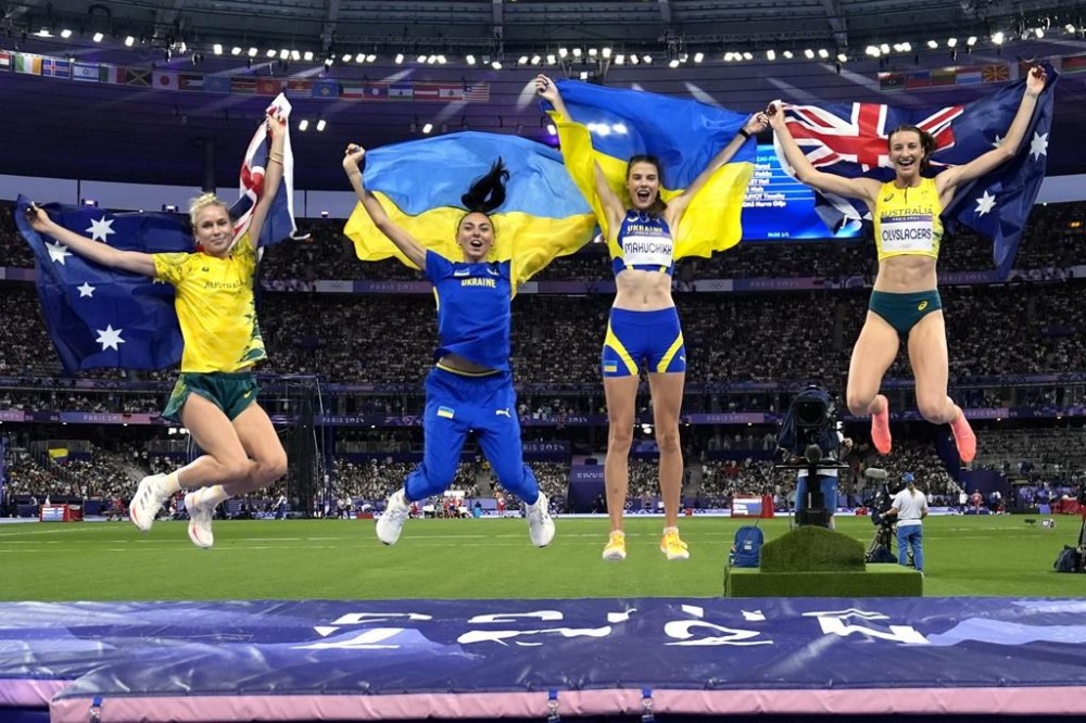 Gold medalist Yaroslava Mahuchikh, second from right, of Ukraine, jumps with silver medalist Nicola Olyslagers, right, of Australia, and bronze medal winners Iryna Gerashchenko, second from left, of Ukraine, and Eleanor Patterson, left, of Australia, following the women's high jump final at the 2024 Summer Olympics, Sunday, Aug. 4, 2024, in Saint-Denis, France. (AP Photo/Matthias Schrader)