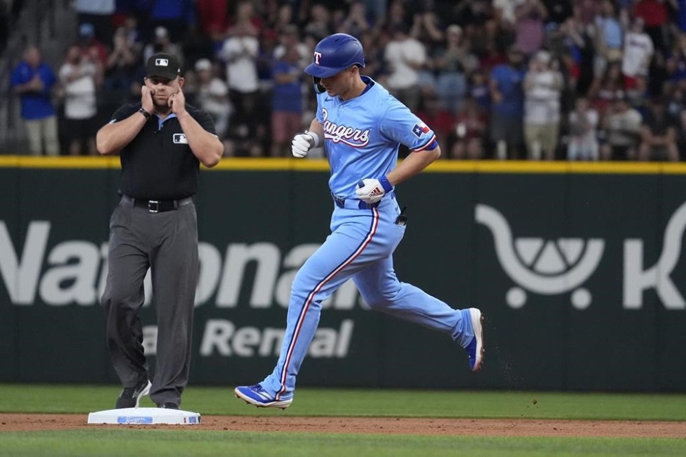 Texas Rangers' Corey Seager, right, runs out his home run past second base umpire John Libka, left, during the first inning of a baseball game against the Boston Red Sox in Arlington, Texas, Sunday, Aug. 4, 2024. (AP Photo/LM Otero)
