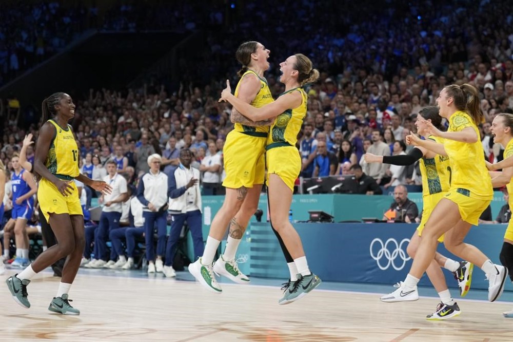 Australia's Alanna Smith, center right, jumps into the arms of Lauren Jackson after drafting France in a women's basketball game at the 2024 Summer Olympics, Sunday, Aug. 4, 2024, in Villeneuve-d'Ascq, France. (AP Photo/Mark J. Terrill)