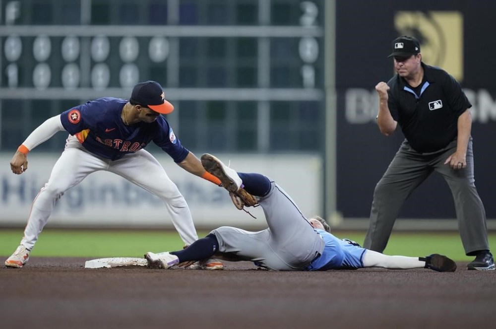 Houston Astros shortstop Jeremy Peña, left, catches Tampa Bay Rays' Taylor Walls, center, who was trying to steal second base as umpire Doug Eddings, right, makes the call during the fourth inning of a baseball game Sunday, Aug. 4, 2024, in Houston. (AP Photo/Kevin M. Cox)