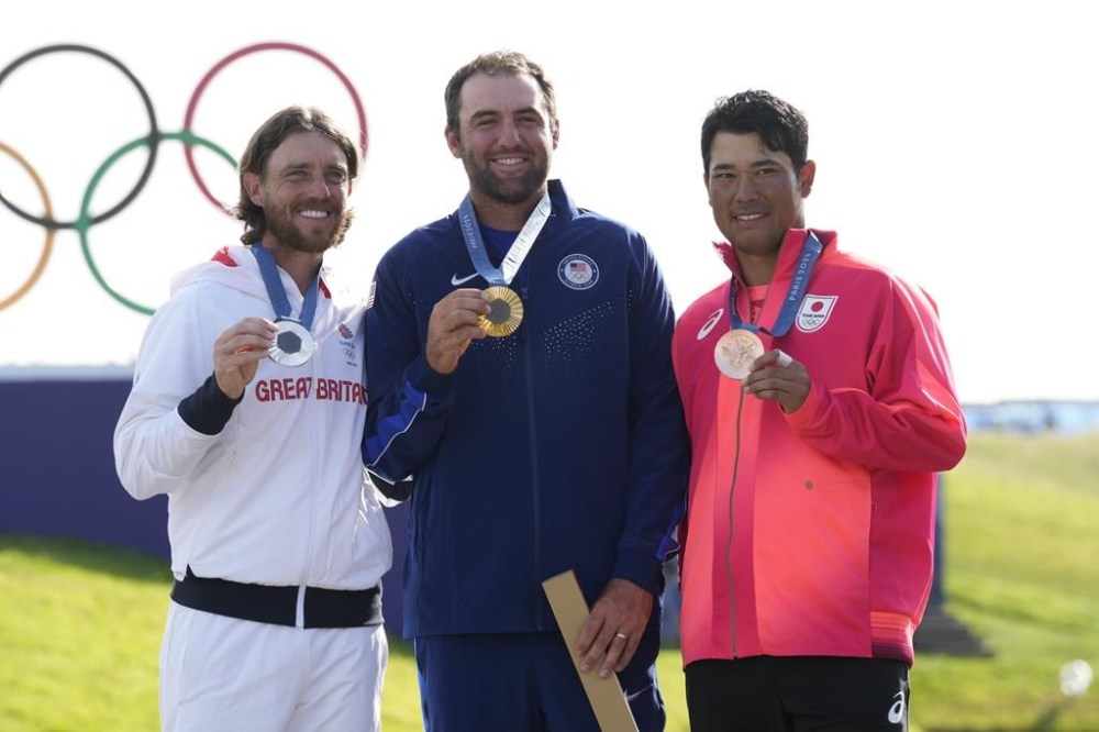 Gold medalist Scottie Scheffler, of the United States, centre, with Tommy Fleetwood, of Britain, silver medal, and Hideki Matsuyama, of Japan, with the bronze medal pose for the media following the medal ceremony for men's golf at the 2024 Summer Olympics, Sunday, Aug. 4, 2024, at Le Golf National in Saint-Quentin-en-Yvelines, France. (AP Photo/Matt York)