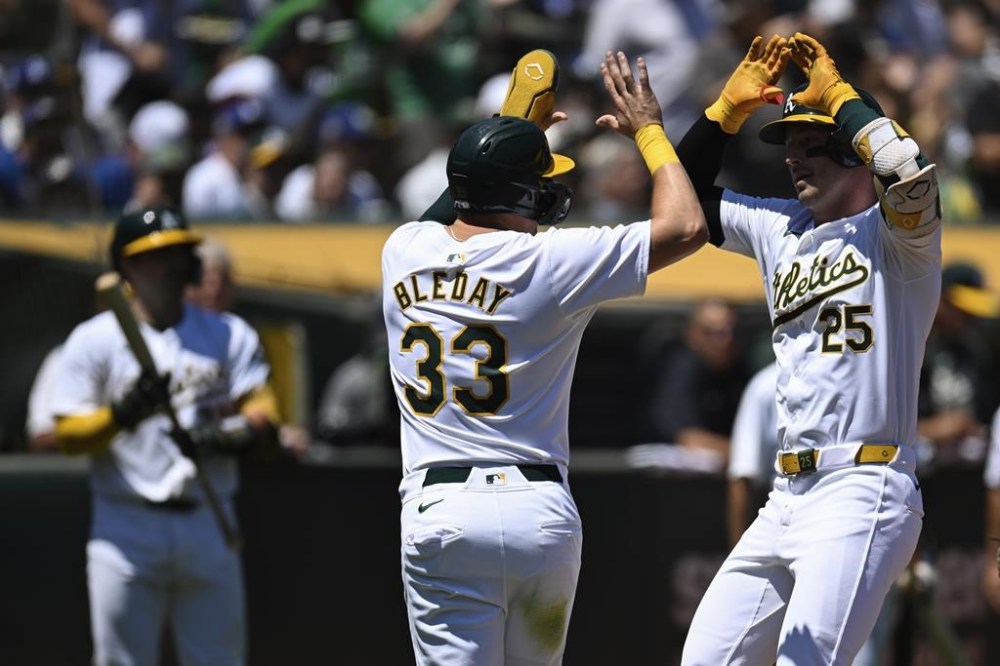 Oakland Athletics' Brent Rooker (25) celebrates with JJ Bleday (33) after hitting a two-run home run against the Los Angeles Dodgers during the first inning of a baseball game Sunday, Aug. 4, 2024, in Oakland, Calif. (AP Photo/Eakin Howard)