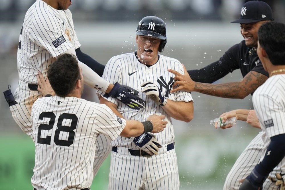 Teammates celebrate with New York Yankees' DJ LeMahieu, center, after he hit a walkoff RBI single during the 10th inning of a baseball game against the Toronto Blue Jays at Yankee Stadium, Sunday, Aug. 4, 2024, in New York. (AP Photo/Seth Wenig)
