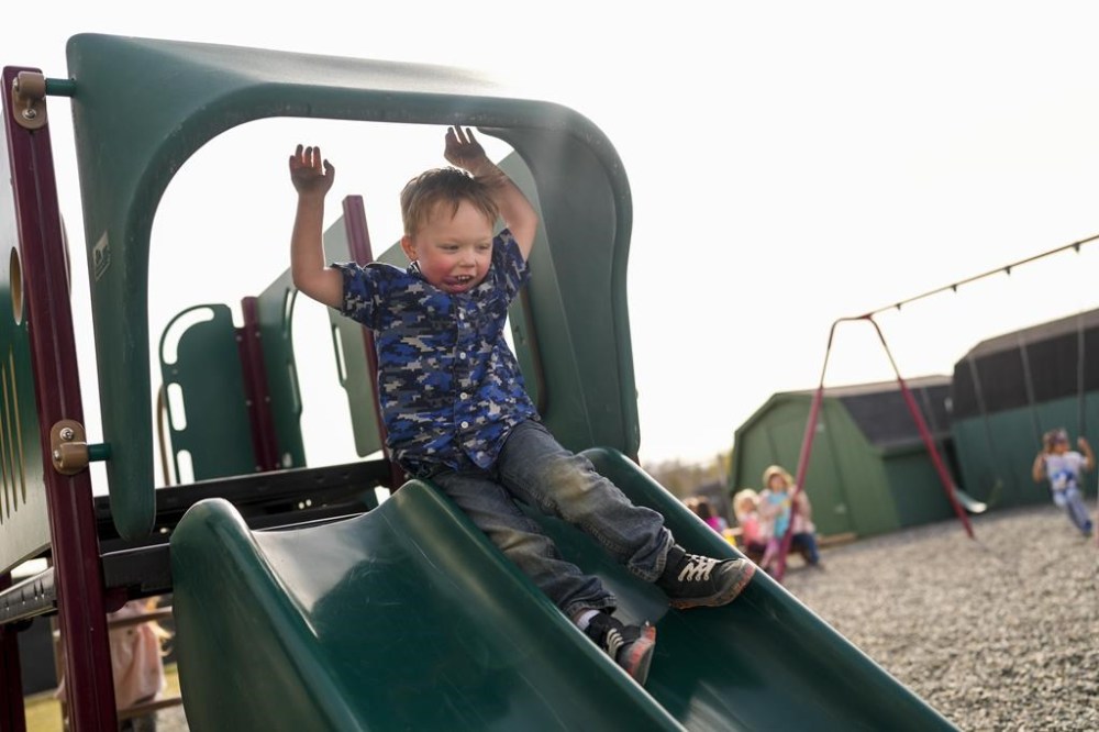 Wayne Mitchell, 5, sticks out his tongue as he goes down a slide during outside time on the last day of school at the Meadow Lakes CCS Early Learning, a Head Start center, Wednesday, May 8, 2024, in Wasilla, Alaska. (AP Photo/Lindsey Wasson)