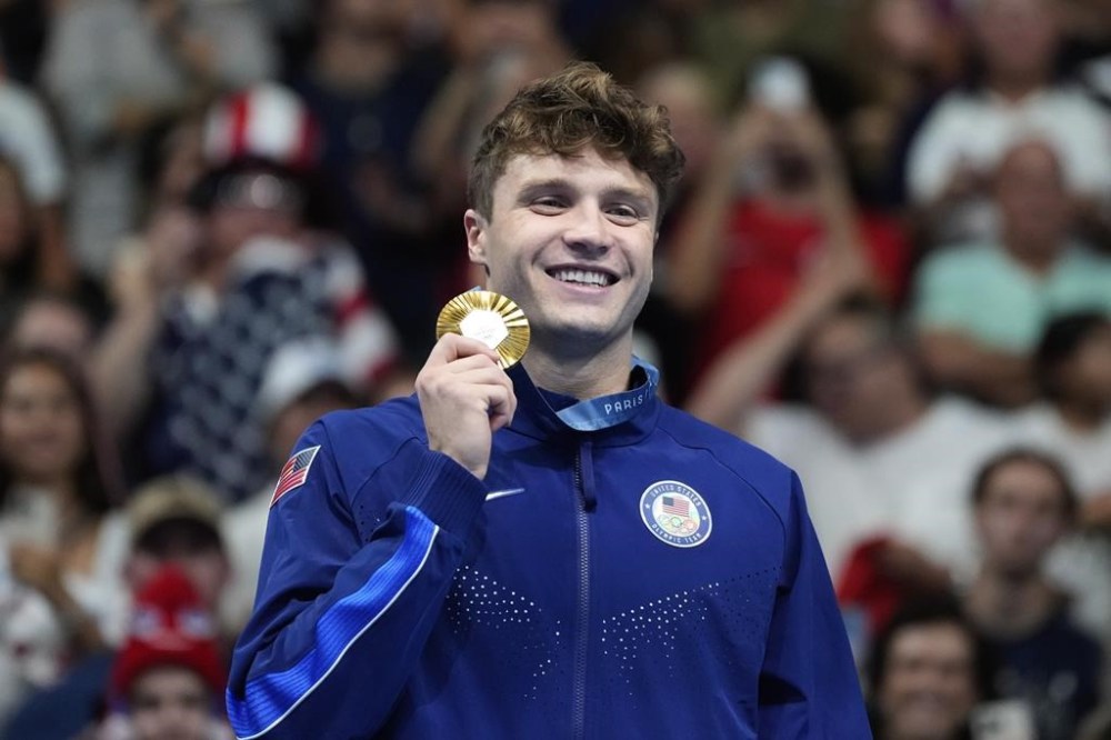 United States' Bobby Finke poses for a photo with his gold medal on the podium for the men's 1500-meter freestyle at the Summer Olympics in Nanterre, France, Sunday, Aug. 4, 2024. (AP Photo/Natacha Pisarenko)