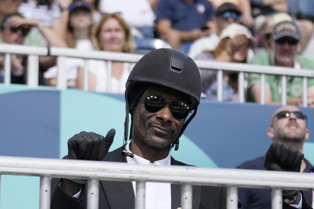 Snoop Dogg thumbs up as he watches the dressage team Grand Prix final at the 2024 Summer Olympics, Saturday, Aug. 3, 2024, in Versailles, France. (AP Photo/Mosa'ab Elshamy)