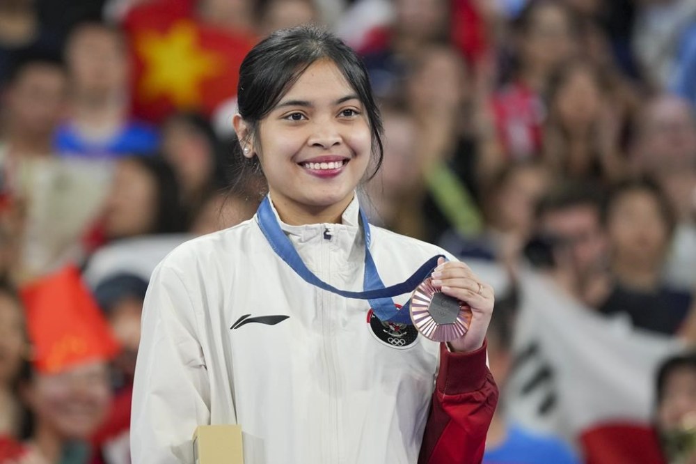 Indonesia's Gregoria Mariska Tunjung celebrates on the podium after wining the bronze medal at the badminton women singles at the 2024 Summer Olympics, Monday, Aug. 5, 2024, in Paris, France. (AP Photo/Kin Cheung)