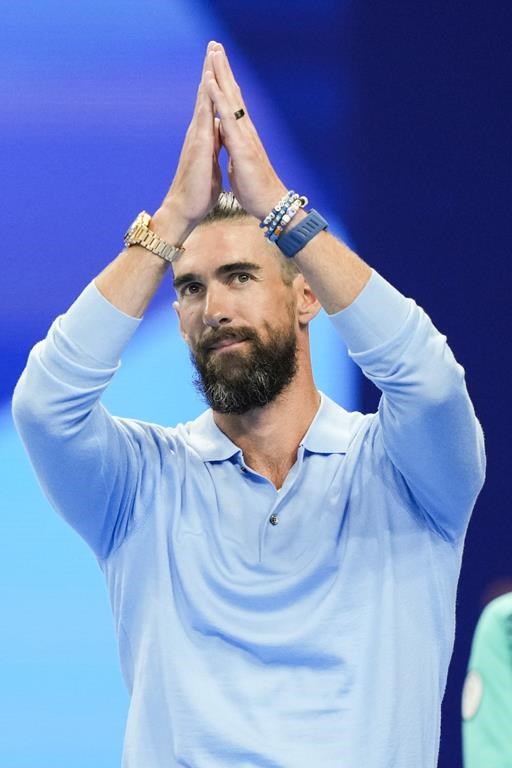 Former Olympic champion Michael Phelps, from the United States, greets fans ahead of the evening swimming session at the 2024 Summer Olympics, Sunday, July 28, 2024, in Nanterre, France. (AP Photo/Martin Meissner)
