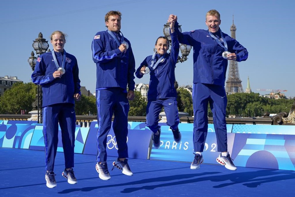 Taylor Knibb, left, Morgan Pearson, Taylor Spivey and Seth Rider, right, of the United States, jump as they hold their medals at the end of the medal ceremony for the mixed relay triathlon at the 2024 Summer Olympics, Monday, Aug. 5, 2024, in Paris, France. (AP Photo/Vadim Ghirda)