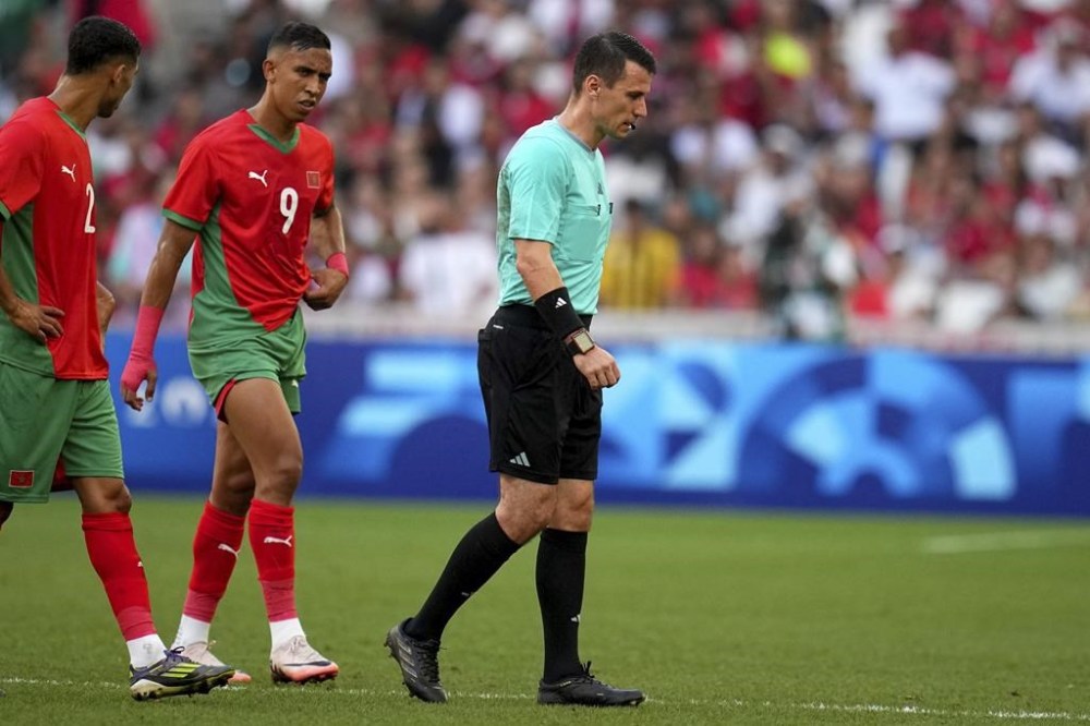 Referee Ilgiz Tantashev, of Uzbekistan, leaves the field after being injured during a men's semifinal soccer match between Morocco and Spain at the 2024 Summer Olympics, Monday, Aug. 5, 2024, at Marseille Stadium in Marseille, France. (AP Photo/Daniel Cole)