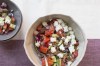 This image shows a traditional Greek salad with fresh cucumbers, tomatoes, feta, onion, and olives. (Katie Workman via AP)