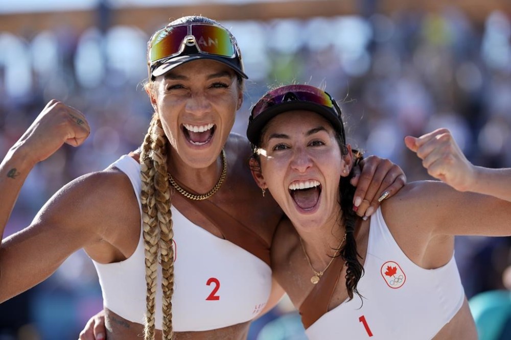 Canada's Brandie Wilkerson, left, and Melissa Humana-Paredes give a celebratory pose after defeating the United States in a beach volleyball match at the 2024 Summer Olympics, Monday, Aug. 5, 2024, in Paris, France. THE CANADIAN PRESS/AP-Robert F. Bukaty