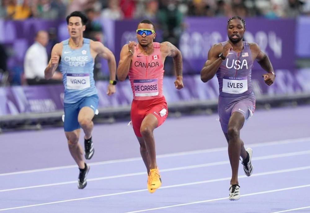 Canada's Andre De Grasse, centre, of Markham, Ont., competes in the men’s 200m qualifying heat at the 2024 Summer Olympics, Monday, Aug. 5, 2024, in Saint-Denis, France. The 29-year-old crossed the finish line in 20.30 seconds to finish second in Heat 6. THE CANADIAN PRESS/Christinne Muschi