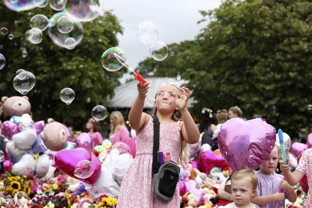 Children form bubbles outside the Town Hall during a vigil to remember the victims of the stabbing attack last Monday in Southport, England, Monday, Aug. 5, 2024. Violence and unrest erupted in cities and towns across Britain, ostensibly in protest of last week's stabbing. (AP Photo/Darren Staples)