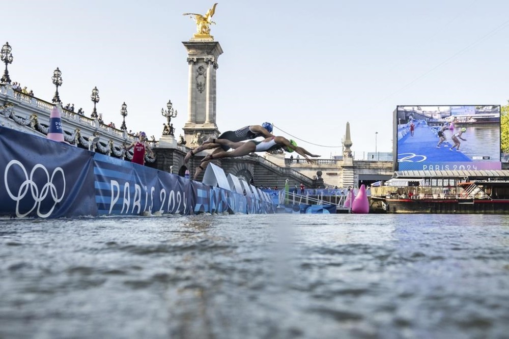Athletes jump into the water to compete in the swimming race in the Seine river, during the mixed relay triathlon, at the 2024 Olympic Games, in Paris, France, Monday, Aug. 5, 2024. (Martin Bureau/Pool Photo via AP)