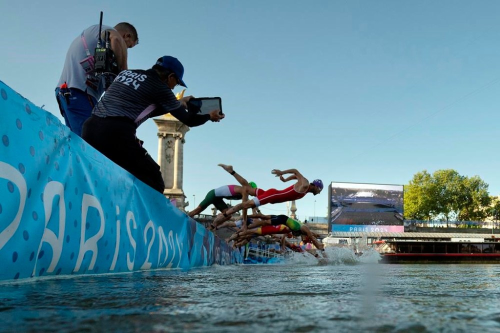 Athletes jump into the water to compete in the swimming race in the Seine river, during the mixed relay triathlon, at the 2024 Olympic Games, in Paris, France, Monday, Aug. 5, 2024. (Martin Bureau/Pool Photo via AP)