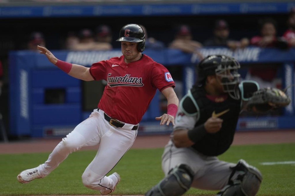 Cleveland Guardians' Lane Thomas slides safely behind Arizona Diamondbacks Gabriel Moreno to score in the first inning of a baseball game in Cleveland, Monday, Aug. 5, 2024. (AP Photo/Sue Ogrocki)