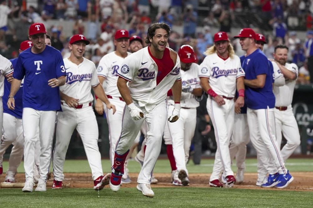 Texas Rangers' Josh Smith, center, celebrates with teammates after hitting a walk-off two-run home run during the tenth inning against the Houston Astros, Monday, Aug. 5, 2024, in Arlington, Texas. (AP Photo/Sam Hodde)