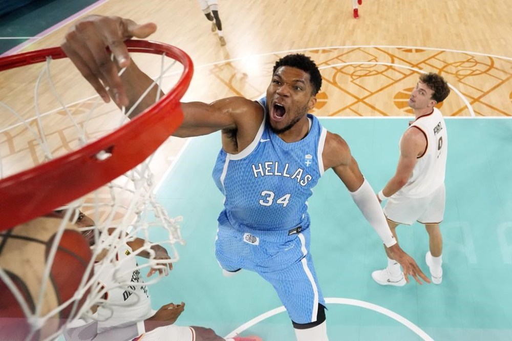 Giannis Antetokounmpo, center, of Greece, dunks as Johannes Thiemann, left, of Germany, and Franz Wagner, of Germany, defend during a men’s basketball game at the 2024 Summer Olympics, Tuesday, Aug. 6, 2024, in Paris, France. (AP Photo/Michael Conroy, Pool)