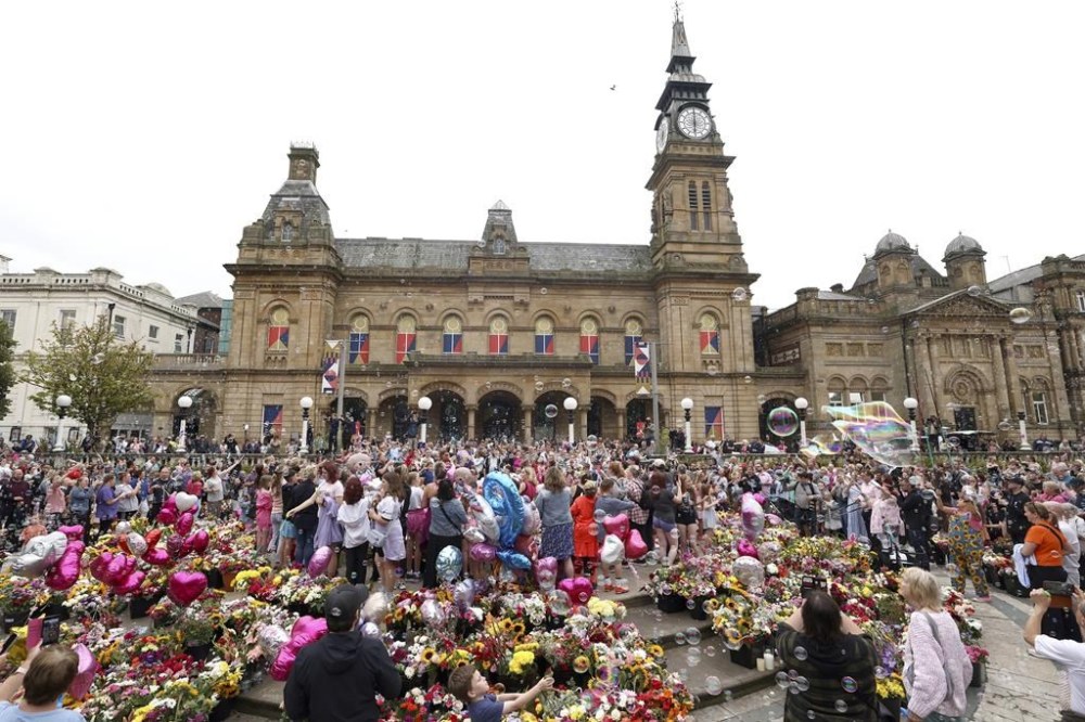Members of the public form bubbles outside the Town Hall during a vigil to remember the victims of the stabbing attack last Monday in Southport, England, Monday, Aug. 5, 2024. Violence and unrest erupted in cities and towns across Britain, ostensibly in protest of last week's stabbing. (AP Photo/Darren Staples)