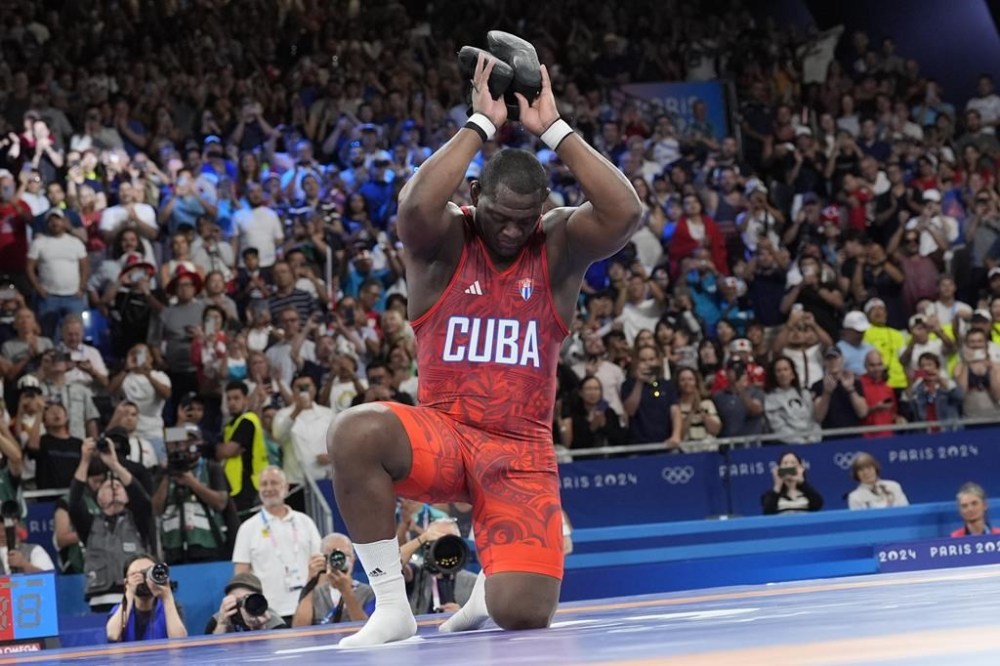 Cuba's Mijain Lopez Nunez removes his shoes as a signal that he is retiring after beating Chile's Yasmani Acosta Fernandez in their men's Greco-Roman 130kg wrestling final match, at Champ-de-Mars Arena, during the 2024 Summer Olympics, Tuesday, Aug. 6, 2024, in Paris, France. (AP Photo/Eugene Hoshiko)