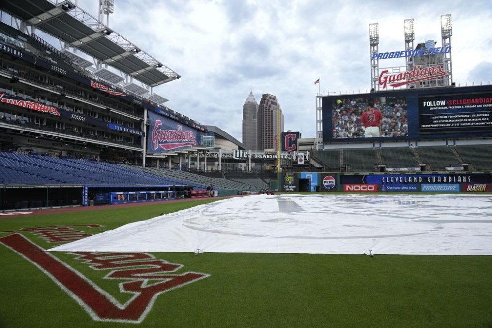 The infield is covered with a tarp before a rain-delayed baseball game between the Arizona Diamondbacks and the Cleveland Guardians in Cleveland, Tuesday, Aug. 6, 2024. (AP Photo/Sue Ogrocki)