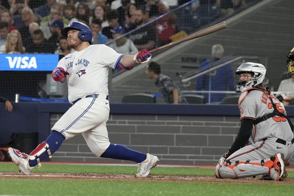 Toronto Blue Jays' Alejandro Kirk hits a three-run home run as Baltimore Orioles catcher Adley Rutschman looks on during sixth inning MLB baseball action in Toronto on Tuesday, August 6, 2024. THE CANADIAN PRESS/Chris Young