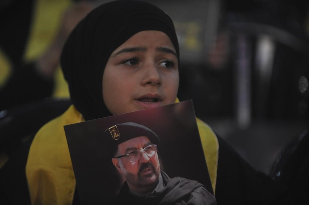 A young girl holds a portrait of top Hezbollah commander Fouad Shukur, who was killed by an Israeli airstrike last week, during a ceremony to commemorate his death in Beirut, Lebanon, Tuesday, Aug. 6, 2024. (AP Photo/Mustafa Jamalddine)