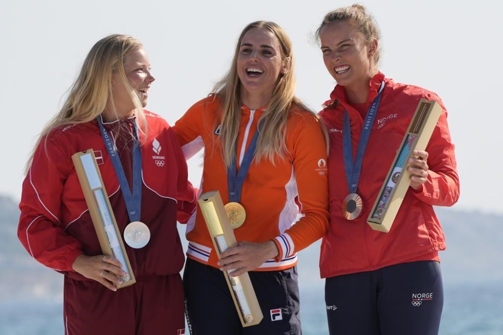 From right, Line Flem Hoest of Norway, bronze medal, Marit Bouwmeester of the Netherlands, gold medal, and Anne-Marie Rindom of Denmark, silver medal, celebrate at the podium during the ILCA 6 women's dinghy class medal ceremony during the 2024 Summer Olympics, Wednesday, Aug. 7, 2024, in Marseille, France. (AP Photo/Jacquelyn Martin)